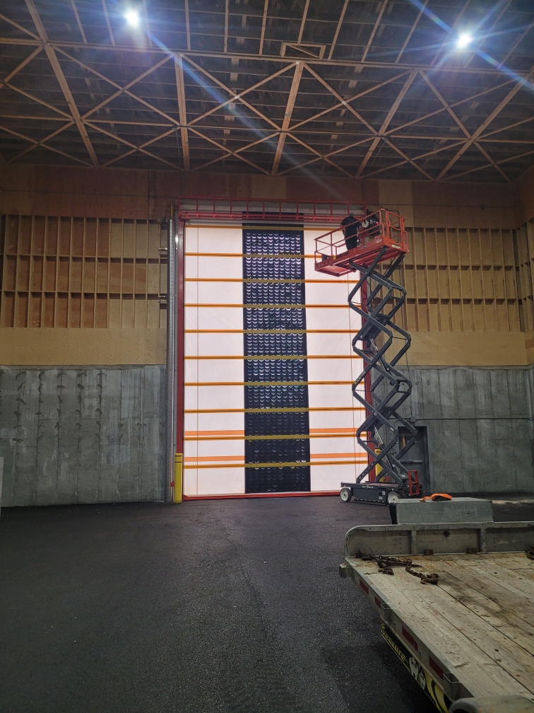 Installation porte à enroulement avec brise-vent